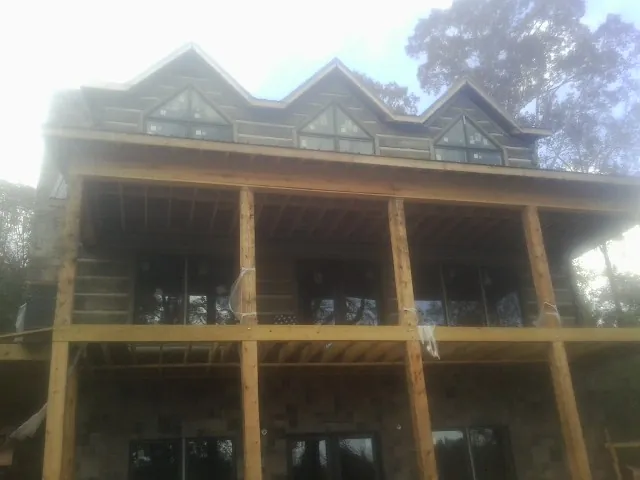 Dormers and porch framing on a large log home under construction — Roof Coating work by our crew in Alpine