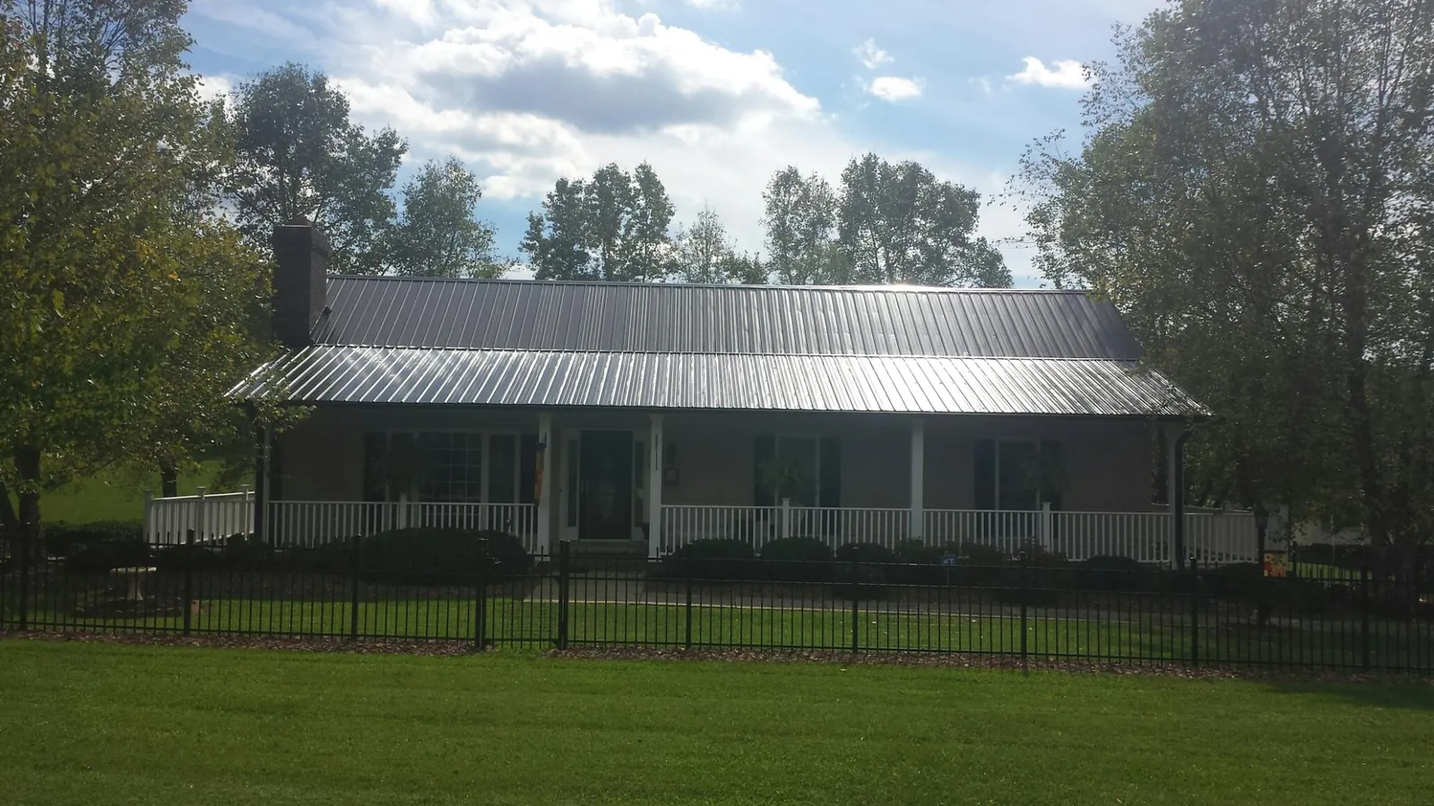 Gray metal roof on a brick ranch with a full width front porch — Gutter Guard Installation work by our crew in Alpine